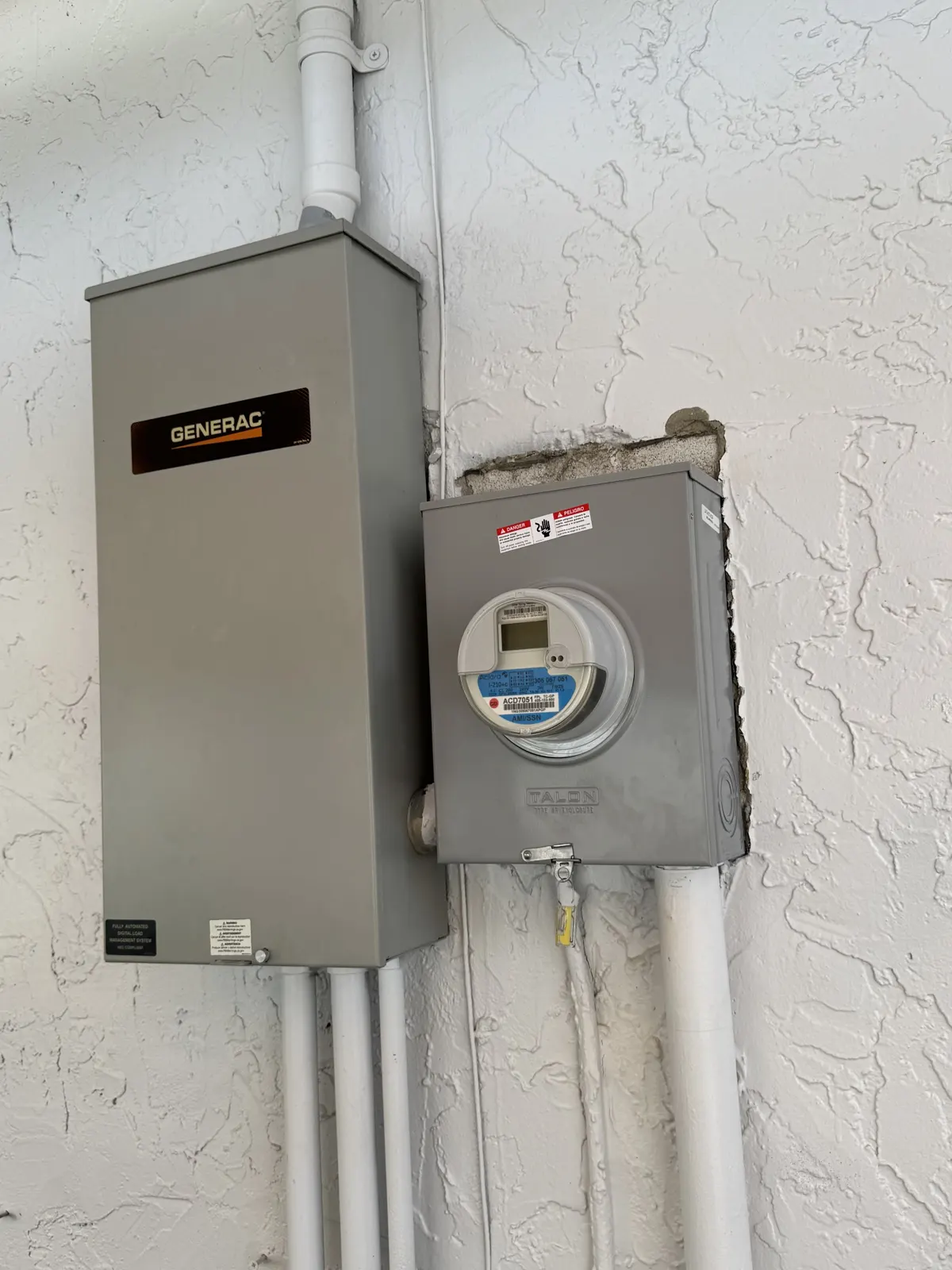 Generac transfer switch mounted beside the meter on a stucco wall