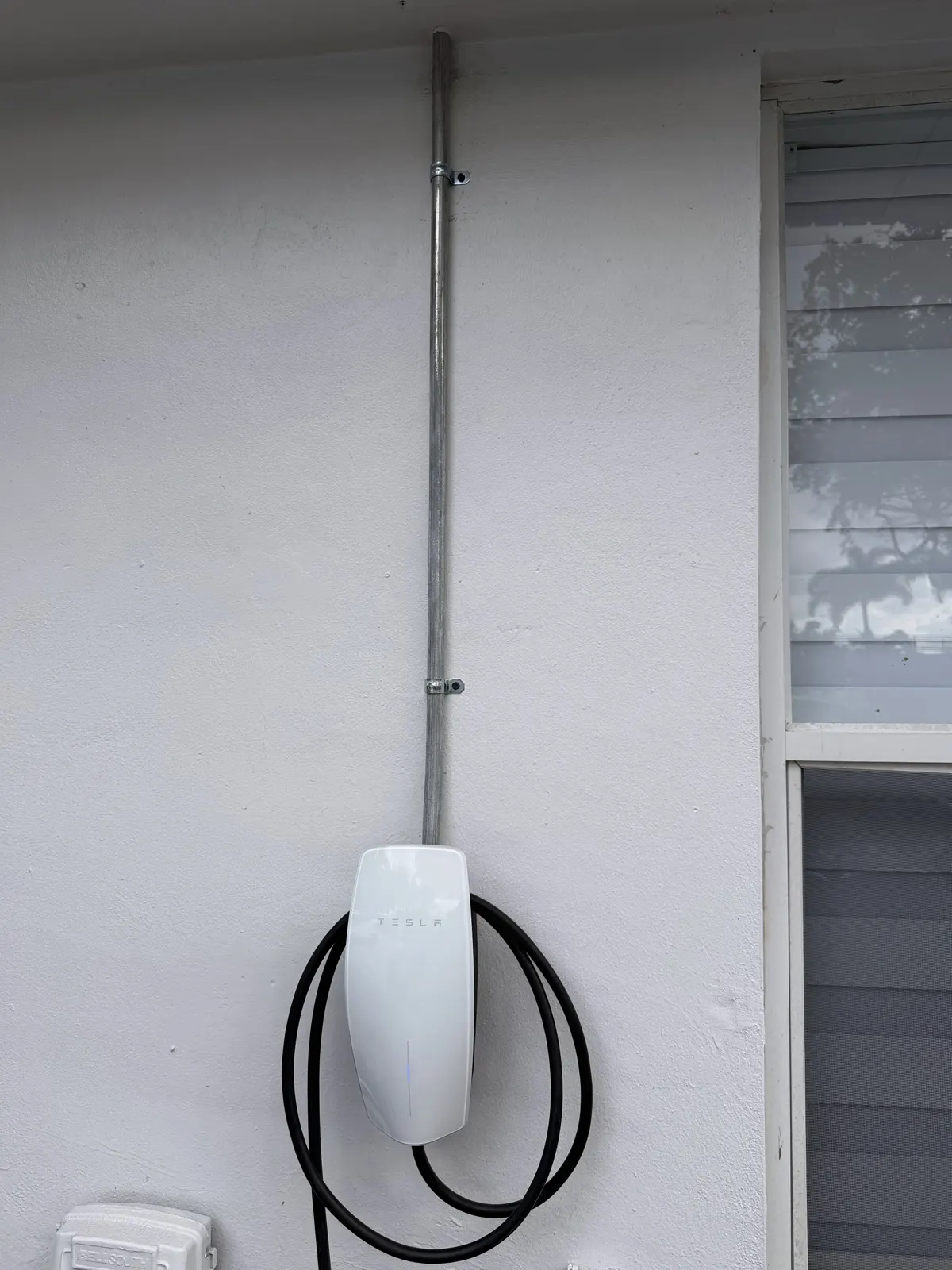 Tesla Wall Connector on an outside wall with conduit from above